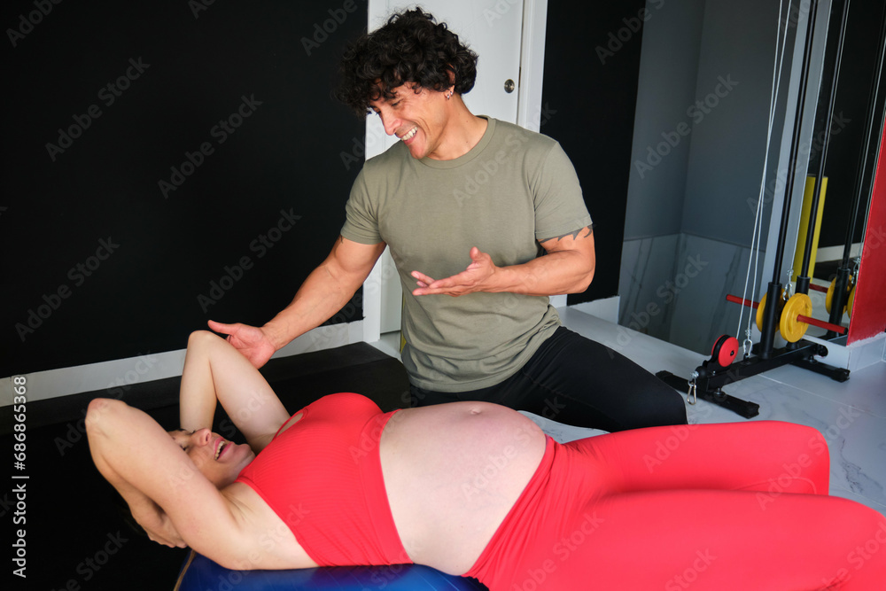Personal coach helping and explaining pregnant woman in gym with stability ball. Personal coach helping and explaining pregnant woman in gym with stability ball.