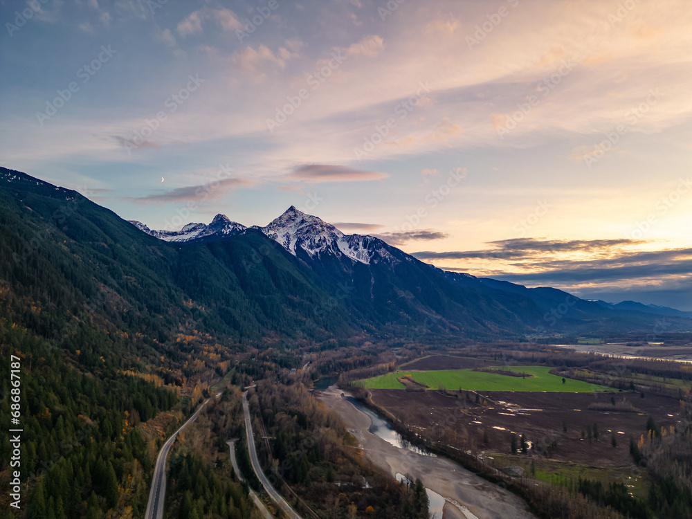 Scenic Road in Valley by the River, surrounded by Mountains. Sunset, Fall Season. Aerial Landscape