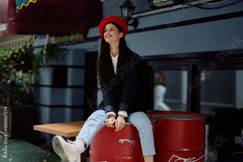 Woman sitting outside a cafe and bar on a city street, stylish fashion image of clothes, vacation and travel, city walk.