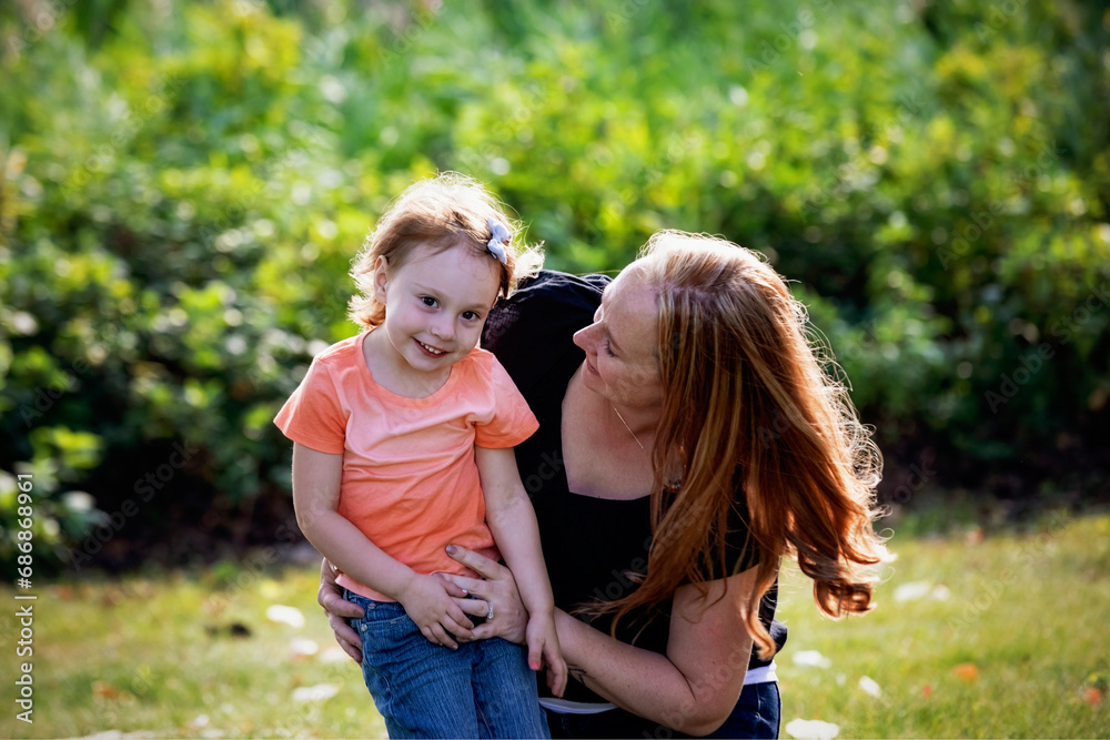 Mother playing with her preschool daughter outdoors in a city park during a warm fall afternoon; Leduc, Alberta, Canada Mother playing with her preschool daughter outdoors in a city park during a warm fall afternoon; Leduc, Alberta, Canada