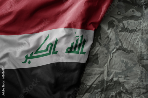 waving flag of iraq on the old khaki texture background. military concept.