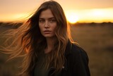 a woman with long hair standing in a field at sunset, australian landscapes, iconic rock and roll imagery, .