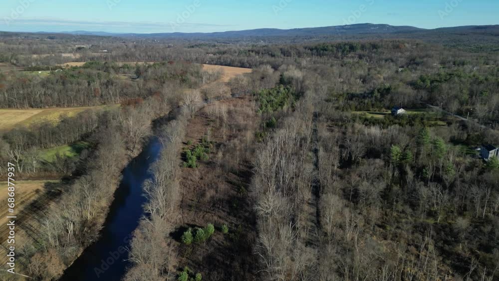 aerial shot above river and path with rural houses and distant mountains (drone flying forward along water, trees) fall, winter, bare trees aerial shot above river and path with rural houses and distant mountains (drone flying forward along water, trees) fall, winter, bare trees