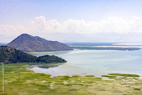 Serene Beauty: Panoramic vew of lake Skardarsko Jezero in Montenegro, featuring green lily pads, reflective mountains, and a pastel summer sky