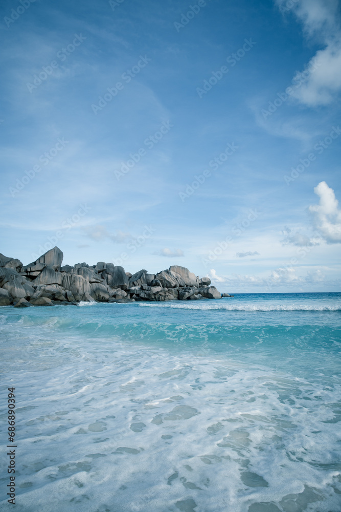 Grand Anse, La Digue Island, Seychelles, wavy tropical paradise on earth, crystal clear tranquil waters, white sand and granitic rocks on the beach. Vacation mood, relaxation, serendipity. Tourism.