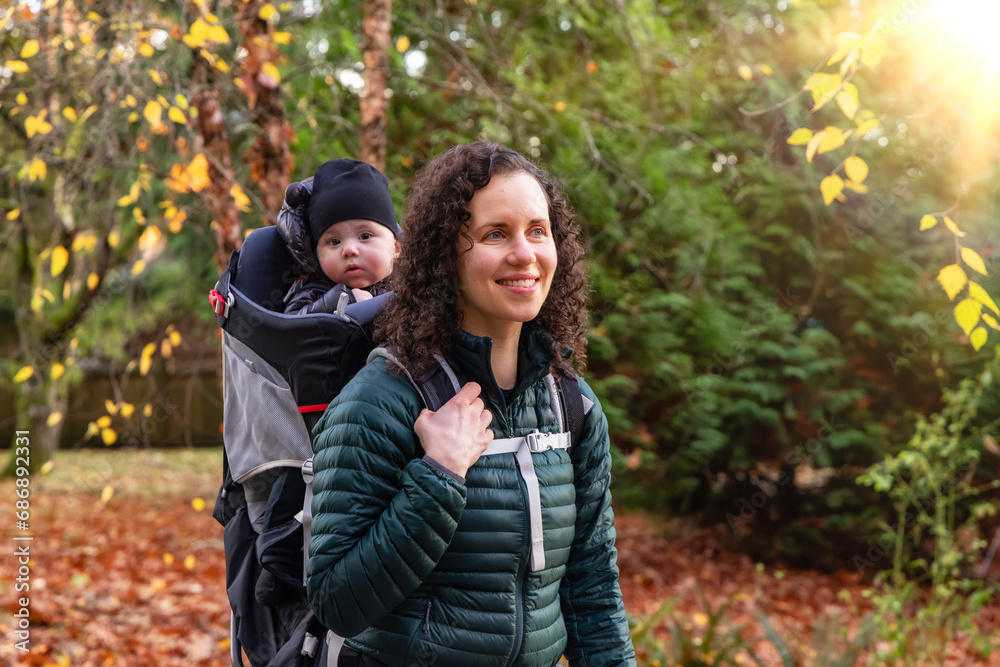 Mother walking in Suburban Neighborhood with Baby in Carrier. Fall Season Mother walking in Suburban Neighborhood with Baby in Carrier. Fall Season