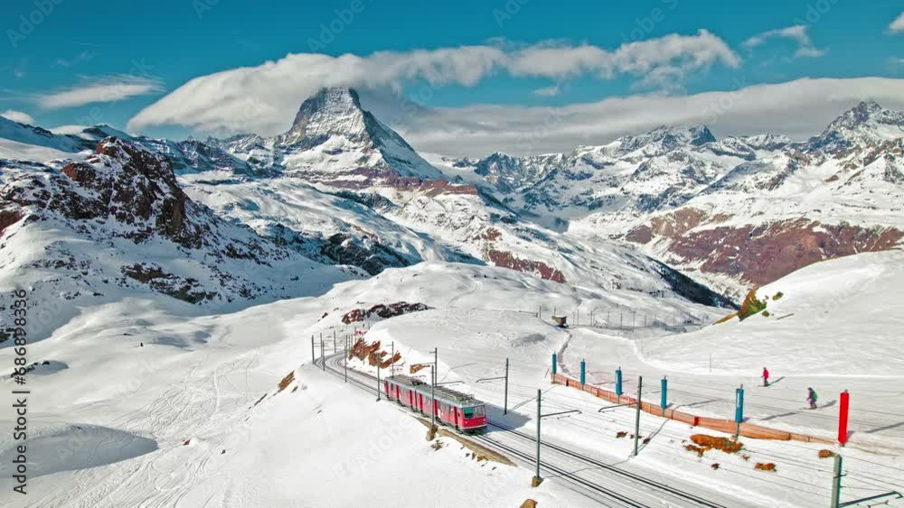 View from above of a passenger red train in the Matterhorn Alps in Europe, Switzerland. Aerial close-up view of a Swiss train with tourists on a railway and Matterhorn mountain in the background. 