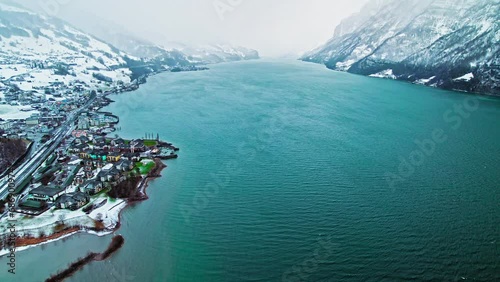 Drone view over Lake Geneva surrounded by colorful houses and the Swiss Alps. Panoramic aerial view of Central Europe's largest lake during winter in ProRes 4K.