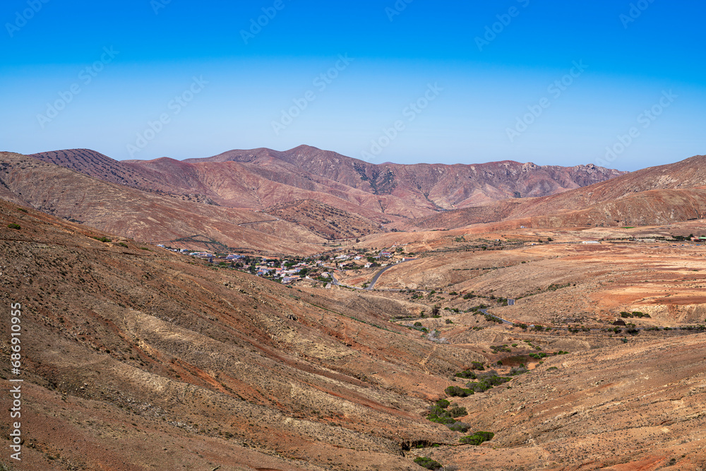 A small town is seen in the desert valley. Photography taken in Fuerteventura, Canary Islands, Spain.