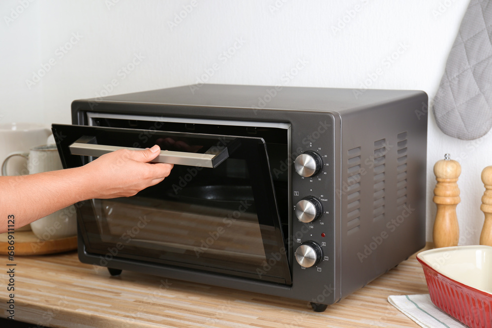 Obraz premium Woman opening electrical oven door indoors, closeup