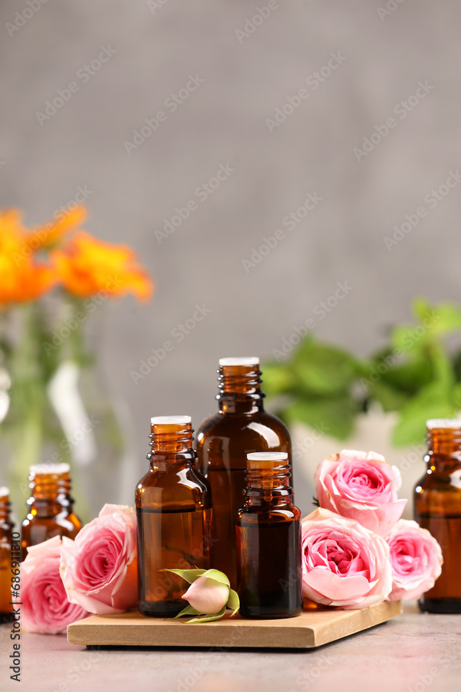 Bottles with essential oil and roses on light table. Space for text Bottles with essential oil and roses on light table. Space for text