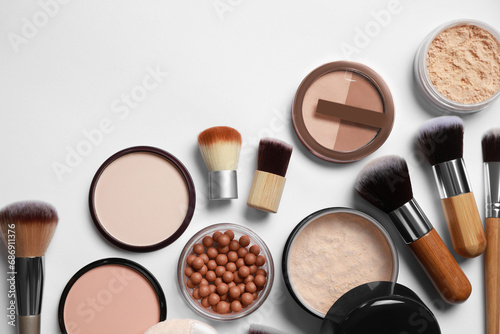 Different face powders and makeup brushes on light background, flat lay