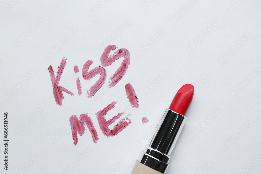 Red lipstick and phrase Kiss Me written on white background, top view Red lipstick and phrase Kiss Me written on white background, top view
