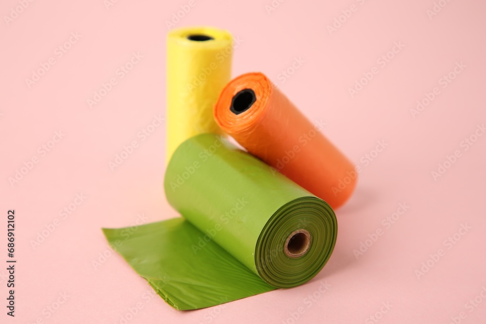 Colorful dog waste bags on pink background, closeup Colorful dog waste bags on pink background, closeup