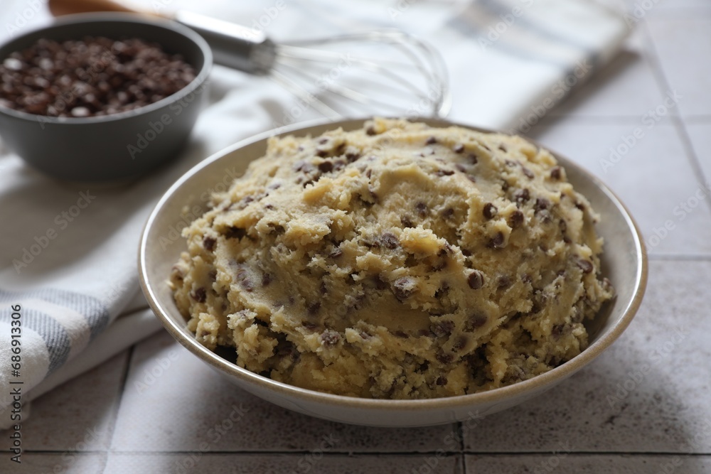 Chocolate chip cookie dough in bowl on tiled table, closeup Chocolate chip cookie dough in bowl on tiled table, closeup