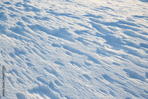 Beautiful winter background with snowy ground. Natural snow texture. Wind sculpted patterns on snow surface.