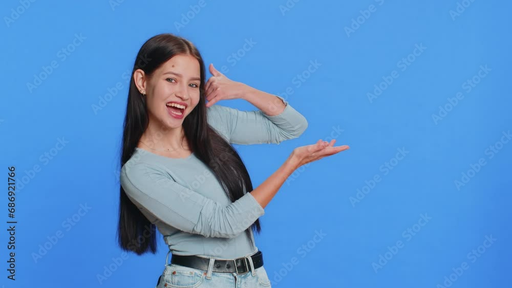 Call me, here is contact number. Caucasian young woman looking at camera doing phone gesture asking for conversation. Hotline online service proposition advertisement. Girl isolated on blue background Call me, here is contact number. Caucasian young woman looking at camera doing phone gesture asking for conversation. Hotline online service proposition advertisement. Girl isolated on blue background