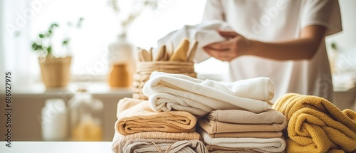 person happily rearranging freshly laundered and neatly folded linens and towels, with the focus on the organized linens and the blurred laundry room