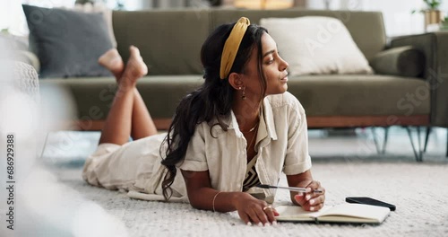 Woman, thinking and writing in journal on living room floor, inspiration and agenda with gen z style, idea and brainstorm. Young, indian person or mindfulness by notepad, pen and creative planning photo