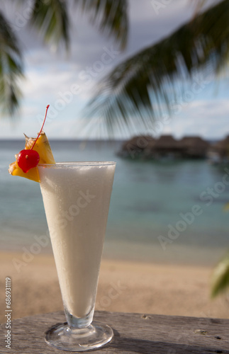 Cocktail on the beach in Tahiti over the ocean with pineapples and cherry and a pina collada 