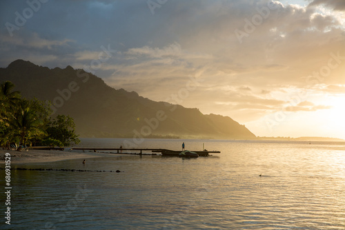 Sunset over the docks on a tropical island with mountains in the background and golden light on fishing docks