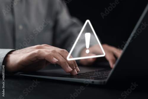 Developer using computer laptop with warning triangle sign for error notification and maintenance concept.