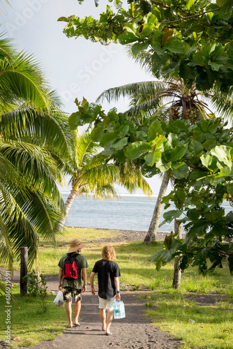 Two friends walk down a tropical path in Tahiti 