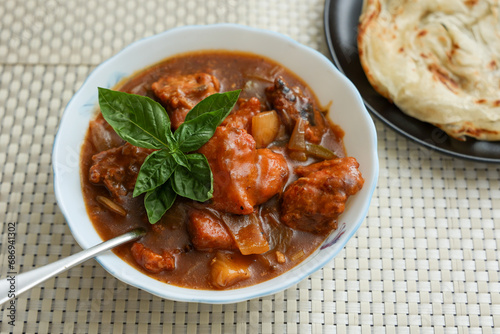 Chilly chicken with Kerala parathas porotta roti parotta barotta naan layered flatbread made from maida whole wheat flour. Eat with spicy Asian chicken beef egg curry gravy. Indian food.