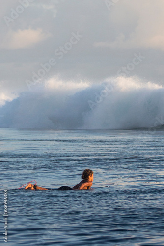 Surfers at sunset wait to catch a wave in Tahiti 
