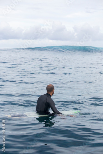 A man waits for a wave in the ocean in Tahiti surfing