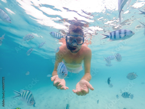 close up of young men at a snorkeling trip in Samaesan Thailand diving underwater with fishes in the coral reef sea pool, watersport adventure, swim activity on a summer beach holiday 