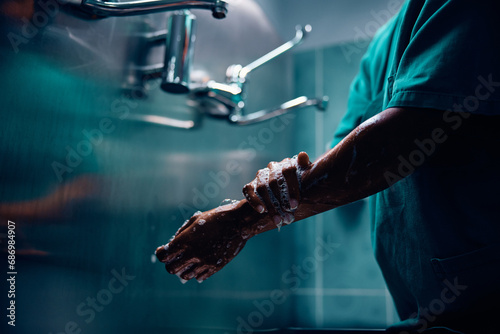 Close up of black surgeon washing her hands at clinic. photo