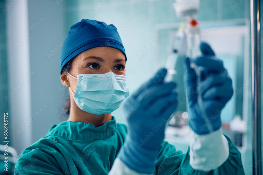 Surgical nurse injecting medicine through IV drip in operating room. Surgical nurse injecting medicine through IV drip in operating room.