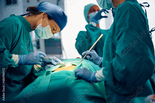 Female surgeon making incision with scalpel in operating room.