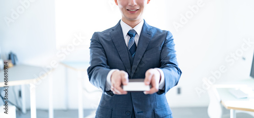 名刺を差し出す若いスーツを着た男性
 photo