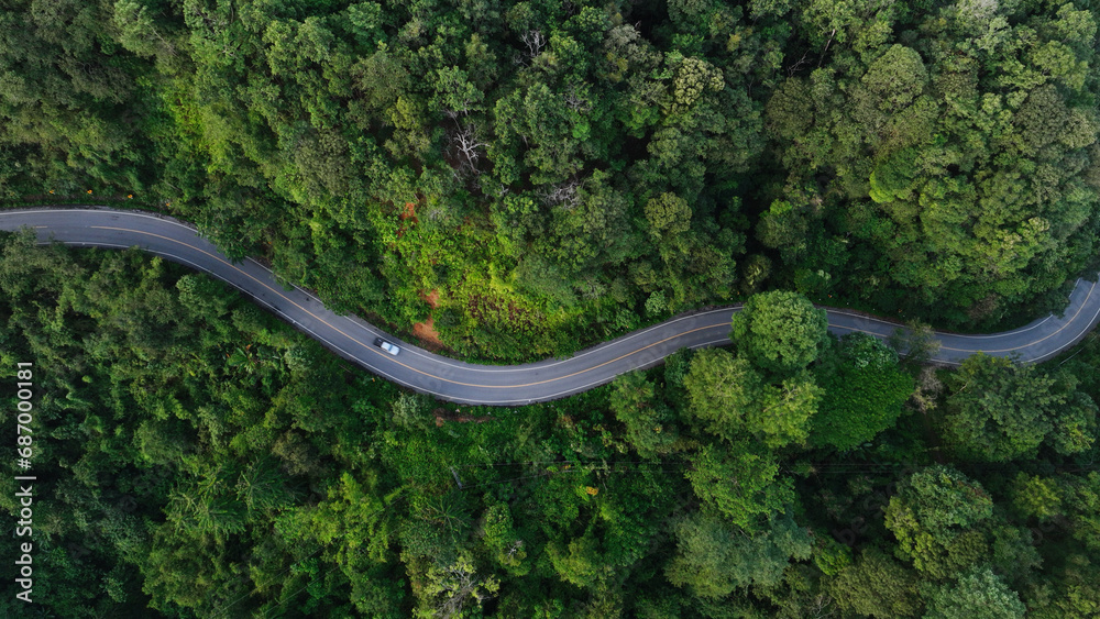 Aerial view of a road in the middle of the forest , road curve construction up to mountain