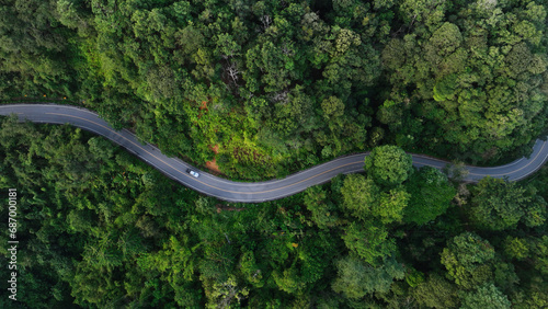 Aerial view of a road in the middle of the forest , road curve construction up to mountain