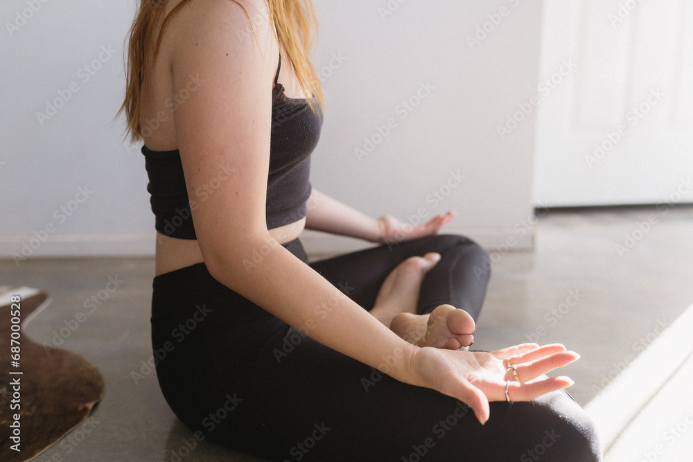 Trendy girl practicing yoga sitting with legs crossed and palms up