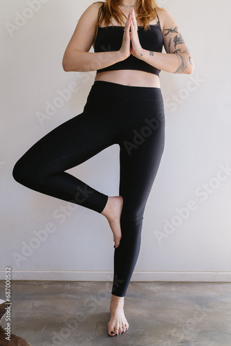 woman doing yoga standing at figure four with hands at heart center