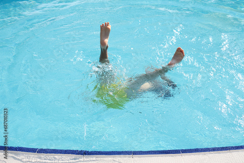 A young swimmer's legs ascend from azure waters, depicting the weightlessness and excitement of a dip