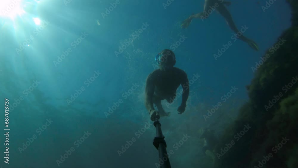 Male friends go snorkeling underwater on a sunny day. First person view from the action camera. Dive freediving