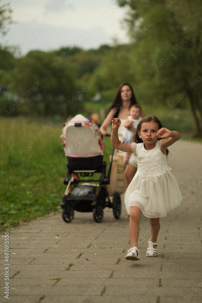 Girl runs ahead as family strolls in the park; a moment of childhood freedom and family outings.