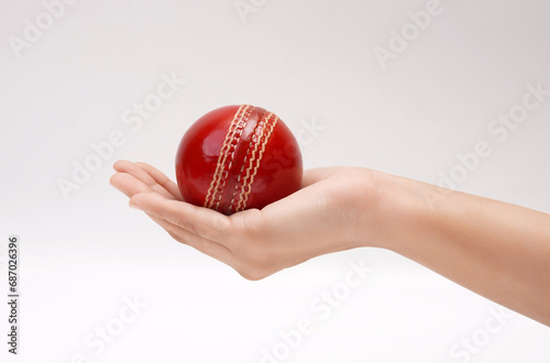 Shiny Red Test Match Leather Stitch Cricket Ball In Women Hand Closeup Picture White Background photo
