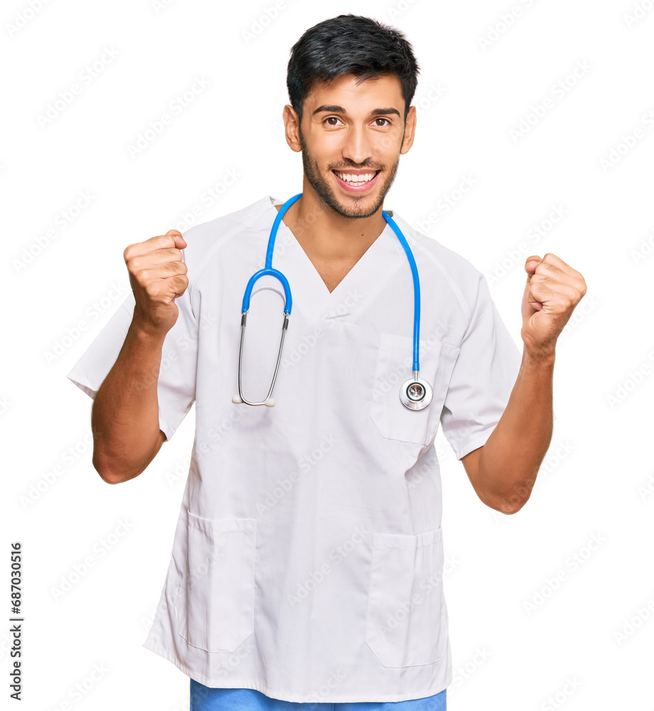 Young handsome man wearing doctor uniform and stethoscope screaming proud, celebrating victory and success very excited with raised arms Young handsome man wearing doctor uniform and stethoscope screaming proud, celebrating victory and success very excited with raised arms