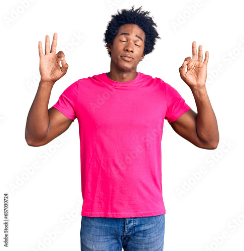 Handsome african american man with afro hair wearing casual pink tshirt relax and smiling with eyes closed doing meditation gesture with fingers. yoga concept.