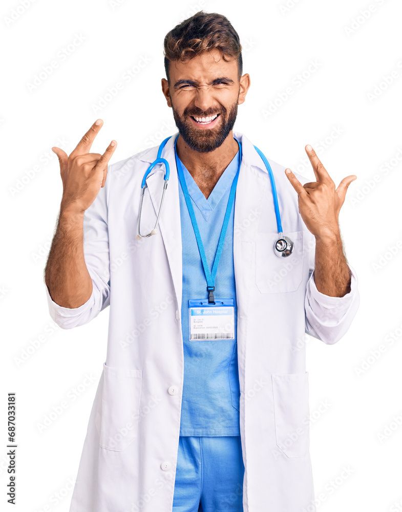 Young hispanic man wearing doctor uniform and stethoscope shouting with crazy expression doing rock symbol with hands up. music star. heavy concept. Young hispanic man wearing doctor uniform and stethoscope shouting with crazy expression doing rock symbol with hands up. music star. heavy concept.
