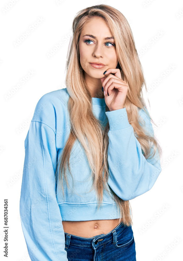 Beautiful young blonde woman wearing casual sweatshirt thinking concentrated about doubt with finger on chin and looking up wondering Beautiful young blonde woman wearing casual sweatshirt thinking concentrated about doubt with finger on chin and looking up wondering