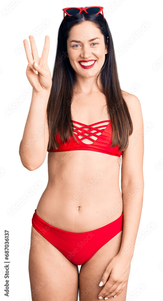 Young beautiful caucasian woman wearing bikini showing and pointing up with fingers number three while smiling confident and happy. Young beautiful caucasian woman wearing bikini showing and pointing up with fingers number three while smiling confident and happy.