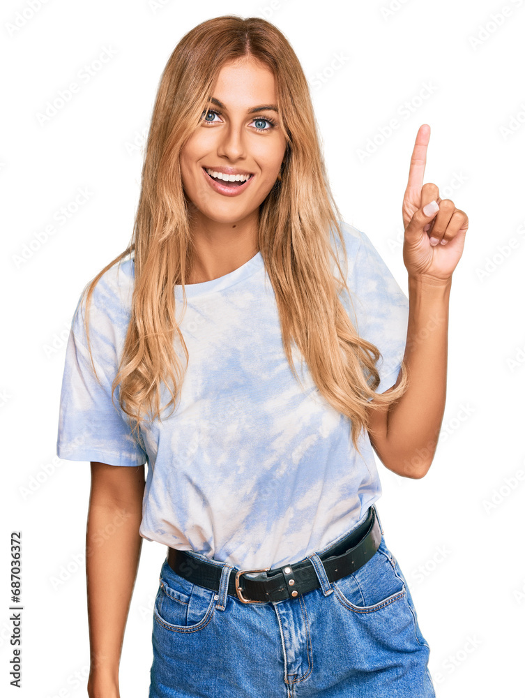 Beautiful blonde young woman wearing casual tie dye shirt pointing finger up with successful idea. exited and happy. number one. Beautiful blonde young woman wearing casual tie dye shirt pointing finger up with successful idea. exited and happy. number one.