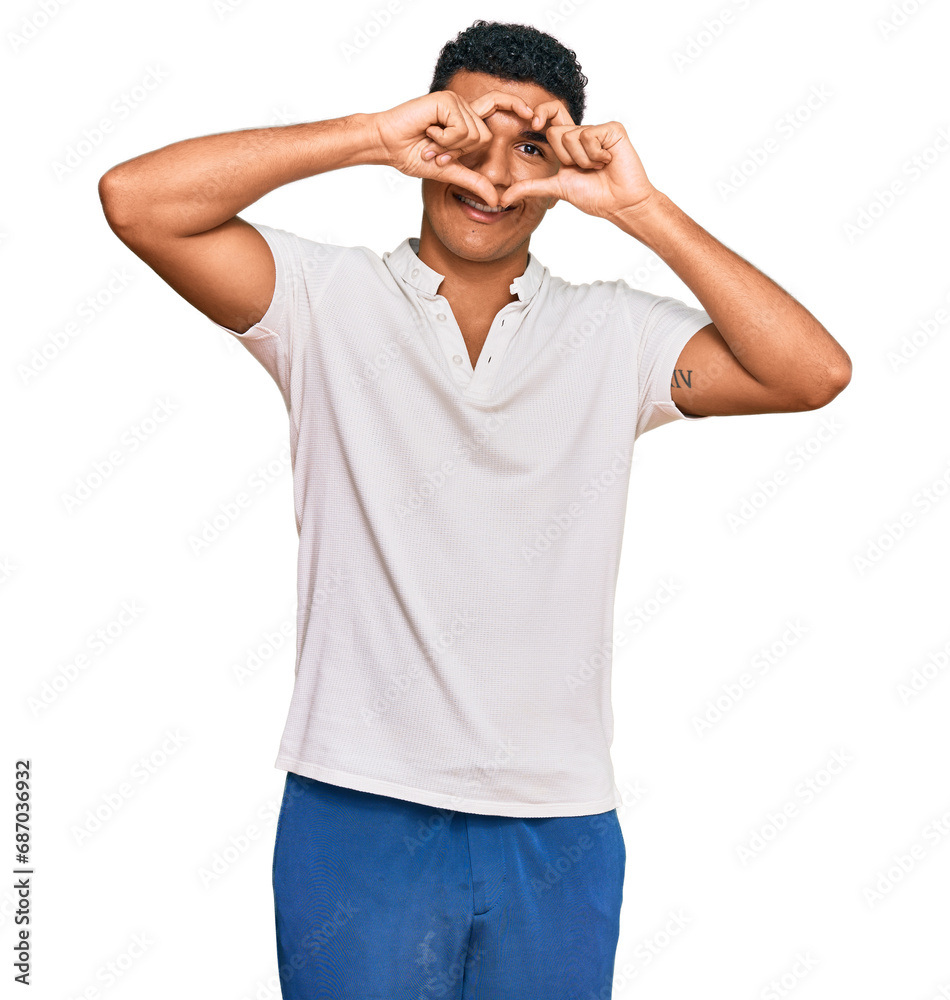 Young arab man wearing casual clothes doing heart shape with hand and fingers smiling looking through sign Young arab man wearing casual clothes doing heart shape with hand and fingers smiling looking through sign